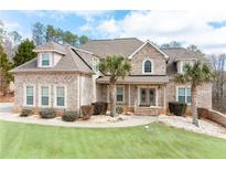 Charming two-story brick home featuring a well-manicured lawn and beautiful landscaping, including palm trees at 1227 Castle Point Sw Ct, Conyers, GA 30094
