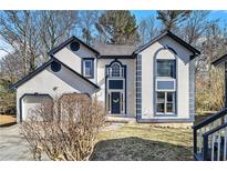 Charming two-story home featuring stucco siding, blue trim, attached garage, and landscaped front yard at 624 Longbow Ct, Stone Mountain, GA 30087