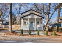 Charming home with a welcoming front porch, white railing, blue front door, and fresh landscaping at 1986 Memorial Se Dr, Atlanta, GA 30317