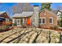 Charming brick home features a stone chimney, a screened porch, and a vibrant orange front door at 1352 Emory Ne Rd, Atlanta, GA 30306