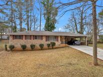 Charming brick home featuring a covered carport, a well-maintained lawn, and mature trees at 2588 Shady Sw Ln, Conyers, GA 30094