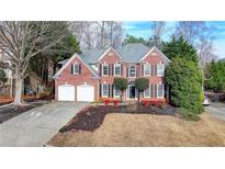 Traditional brick home featuring a two-car garage and mature landscaping at 3723 Mossbrook Ter, Suwanee, GA 30024