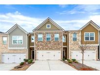 Charming townhomes featuring brick and siding exteriors with attached garages, set under a bright blue sky at 2230 Mulsanne Dr, Lithonia, GA 30058