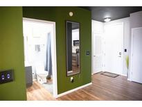 Hallway features wood-look floors, olive-colored accent wall, modern fixtures, and entrance to the bathroom and kitchen at 898 Oak Sw St # 1410, Atlanta, GA 30310