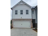 View of garage exterior with brick and white siding; three windows above the two-car garage at 537 Tuskegee St # 48, Mcdonough, GA 30252