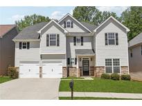 Charming two-story home featuring a manicured lawn, stone accents, and a two-car garage at 4416 Water Mill Dr, Buford, GA 30519