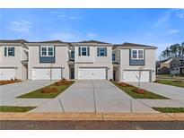 New townhome exteriors featuring a two-car garage, blue shutters, and freshly installed landscaping at 204 Sanctuary Dr, Mcdonough, GA 30253