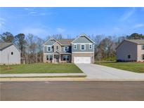Charming two-story home featuring a brick and siding exterior, a well-manicured lawn, and a two-car garage at 120 Felicity Pike, Locust Grove, GA 30248
