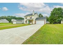 Charming two-story home featuring a long driveway, attached garage, and well-maintained lawn at 5484 Denny Dr, Atlanta, GA 30349