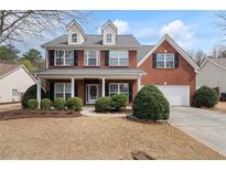 Charming two-story red brick home featuring a welcoming front porch and attached garage at 923 Port West Dr, Auburn, GA 30011