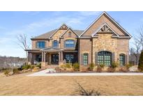 Beautiful brick and stone home with a covered front porch and manicured lawn at 13425 Bishops Ct, Roswell, GA 30075