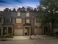 Charming brick townhome featuring a two-car garage, covered entry, and dormer windows at 1649 Southgate Mill Dr, Duluth, GA 30096