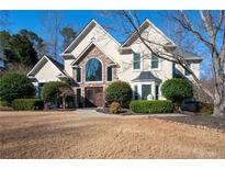 Stunning two-story home with a stone facade, arched window, and mature landscaping at 1850 Kirkmont Nw Dr, Marietta, GA 30064