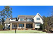 Charming, light-colored two-story home featuring a covered front porch, swing, and meticulously landscaped yard at 109 Daxton Dr, Canton, GA 30115