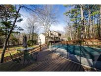 Outdoor pool with a security fence alongside a wooden deck and lush surrounding trees and a backyard at 150 Karina Pl, Canton, GA 30115