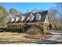 Brick two story home featuring detailed dormers, lush landscaping, and a winding driveway at 11710 Mountain Laurel Dr, Roswell, GA 30075