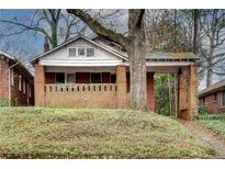 Charming brick home with a covered front porch surrounded by mature trees and greenery at 1523 Melrose Sw Dr, Atlanta, GA 30310