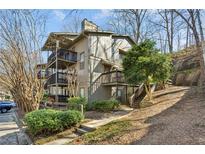Multi-level condo building with private balconies, mature trees, and lush landscaping on a sunny day at 2701 Cumberland Se Ct, Smyrna, GA 30080