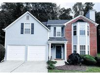 Charming two-story home featuring a blend of brick and light blue siding, a two-car garage and well-maintained landscaping at 5895 Water Oaks Dr, Austell, GA 30106