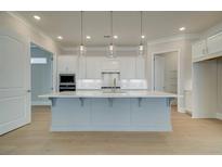 Bright kitchen features a large island with quartz countertops and modern pendant lighting at 7220 Winderlea Ln, Cumming, GA 30040