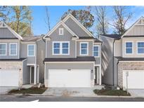 Charming two-story townhome featuring a gray facade, well-manicured lawn, and an attached two-car garage at 686 Smokey Quartz Way, Kennesaw, GA 30144