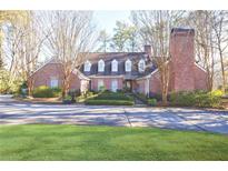 Charming brick home with manicured lawn, fenced entrance, dormer windows, and a prominent chimney at 1762 Nancy Creek Bluff, Atlanta, GA 30305