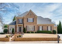 Two-story brick home featuring a manicured lawn, brick stairs, and gray shutters at 5029 Tarry Glen Dr, Suwanee, GA 30024