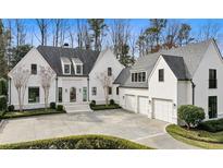 Stunning white home with a circular driveway, manicured landscaping, and an attached three-car garage at 100 Tuxedo Nw Ter, Atlanta, GA 30342