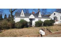 Quaint single-Gathering home featuring a gabled roof, bushes, and a mailbox in the front yard at 1385 Womack Ave, Atlanta, GA 30344