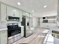 Charming kitchen features stainless steel appliances, white counters and stylish, light green cabinetry at 101 Summer Pond Trl, Lawrenceville, GA 30046