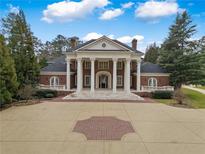 Stately brick home with a large circular driveway, white columns, and manicured landscaping at , Roswell, GA 30075