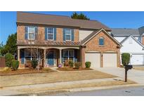 Charming brick two-story home with a well-manicured front yard and a two-car garage at 707 Aroura Dr, Woodstock, GA 30188