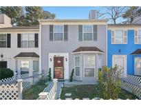 Charming two-story townhouse featuring gray siding, bay window and a lovely picket fence at 5607 Stonington Trace Pkwy, Stone Mountain, GA 30087