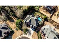 Aerial view of a red brick home with a large roof and backyard pool in a leafy neighborhood at 389 Mill Creek Ne Bnd, Atlanta, GA 30307