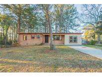 Charming single-story home with brick facade, large windows, and mature trees on a sunny day at 546 W Sherwood Dr, Riverdale, GA 30274