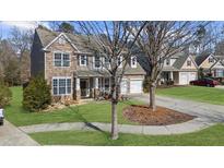 Charming two-story home featuring a stone facade, well-manicured lawn, and a two-car garage, situated on a tree-lined street at 6909 Island Pointe Dr, Buford, GA 30518