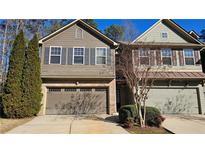 Traditional two-story townhome featuring a two-car garage, brick accents, and neutral toned siding at 115 Sunset Ln, Woodstock, GA 30189