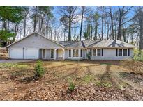 Charming single-story home with a two-car garage and a well-maintained front yard surrounded by mature trees at 1876 Winding Creek Sw Ln, Marietta, GA 30064