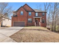 Two-story brick home featuring an attached garage and a well-manicured front yard on a sunny day at 3313 Alhambra Cir, Hampton, GA 30228