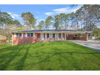 Charming red brick home features a well-manicured lawn and inviting covered front porch at 4218 Hideaway Dr, Tucker, GA 30084