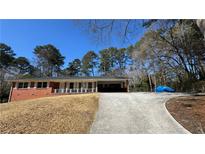 Cozy brick home featuring a large front yard, covered carport, and a spacious driveway for ample parking at 4218 Hideaway Dr, Tucker, GA 30084