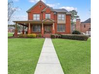 Stunning two-story red brick home with a covered front porch and lush green lawn at 1694 Jamie Leigh Ct, Snellville, GA 30078