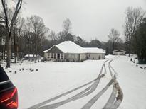 Single-story home with a snow-covered roof, a covered front porch, and a large front yard at 332 Mount Zion Rd, Oxford, GA 30054