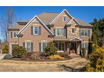 Stunning two-story brick home featuring a stone facade, wood accents, and meticulously landscaped front yard at 5650 Copper Creek Pass, Cumming, GA 30040