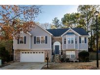 Charming two-story home with light gray siding, a stone facade, a well-manicured lawn, and an attached two-car garage at 1971 Commonwealth Way, Grayson, GA 30017