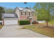 Charming two-story brick home with solar panels, manicured landscaping, and a two-car garage at 12947 Dunand Blvd, Hampton, GA 30228