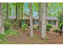 Charming single-story brick home with a well-maintained yard and a front porch surrounded by mature trees at 8980 Country Club Dr, Douglasville, GA 30134
