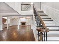 Bright entryway features hardwood floors, staircase with iron railing, and view into the living and kitchen area at 8900 River Trace Dr, Johns Creek, GA 30097