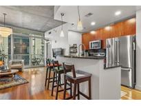 Modern kitchen with stainless steel appliances and breakfast bar seating overlooking the hardwood floor living area at 44 Peachtree Ne Pl # 1225, Atlanta, GA 30309