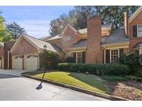Charming brick townhome featuring a two-car garage and manicured front lawn and a classic brick chimney at 52 Ivy Chase Ne, Atlanta, GA 30342